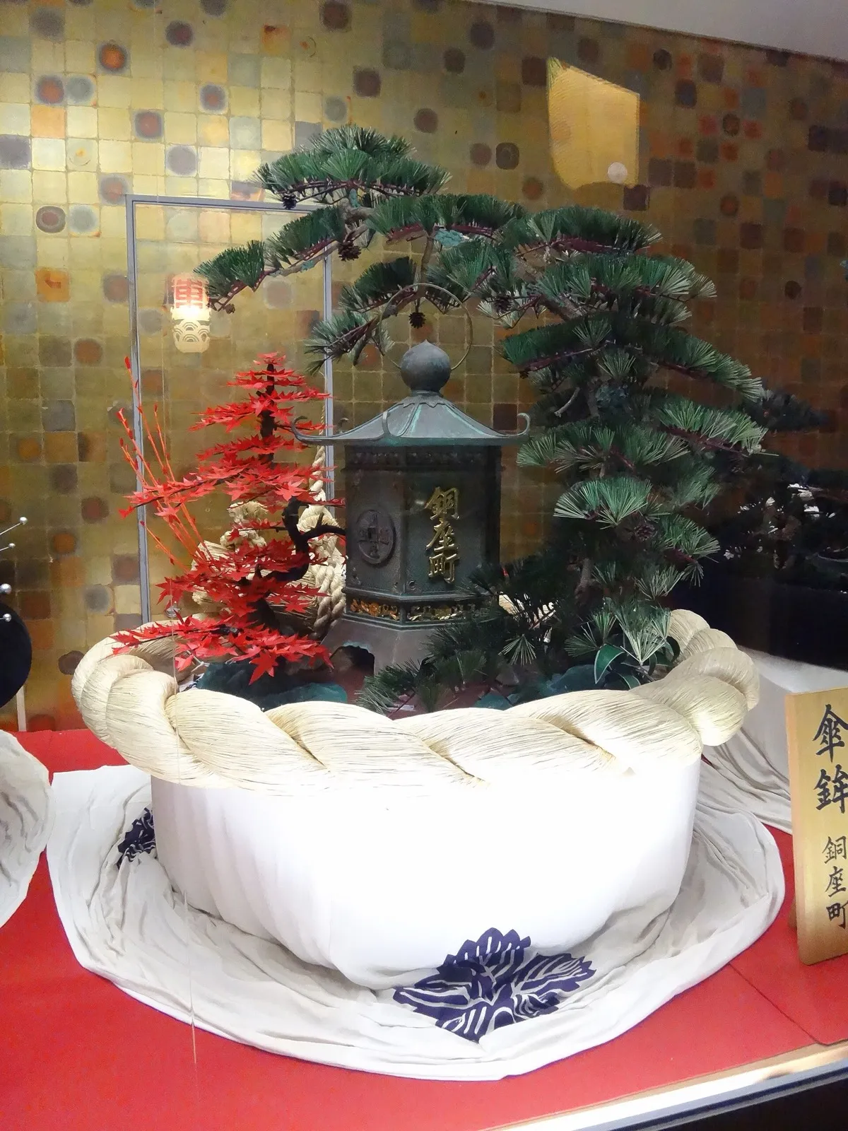 長崎伝統芸能館に展示されていた銅座町の傘鉾（2012年撮影）。老松の下に「銅座町」の銅灯籠と紅葉