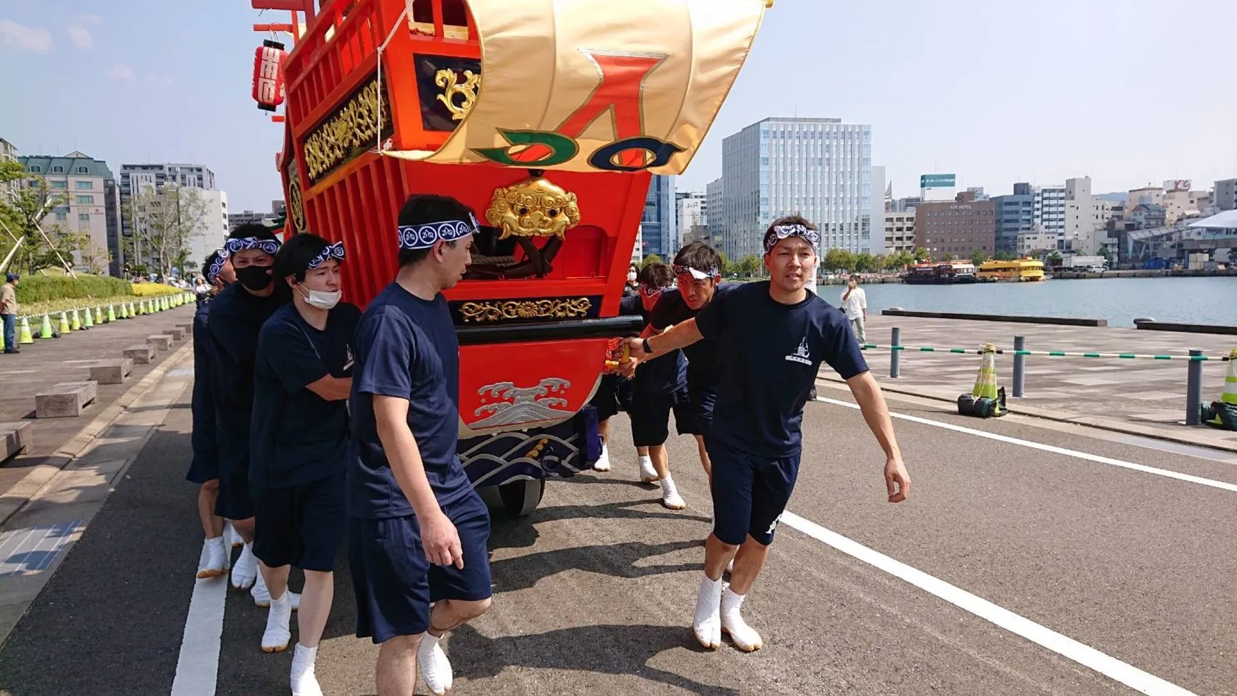 御朱印船を押して進む紺のTシャツの人たち