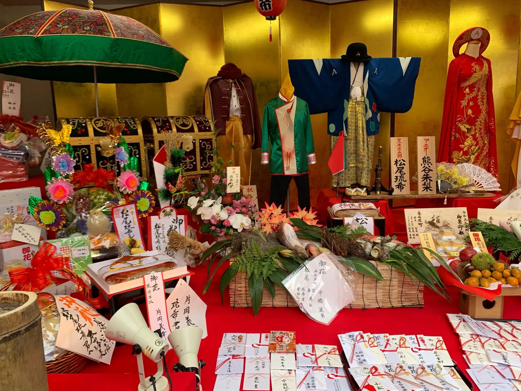 金屏風の前に飾られた衣装と傘、届いたお祝いの品