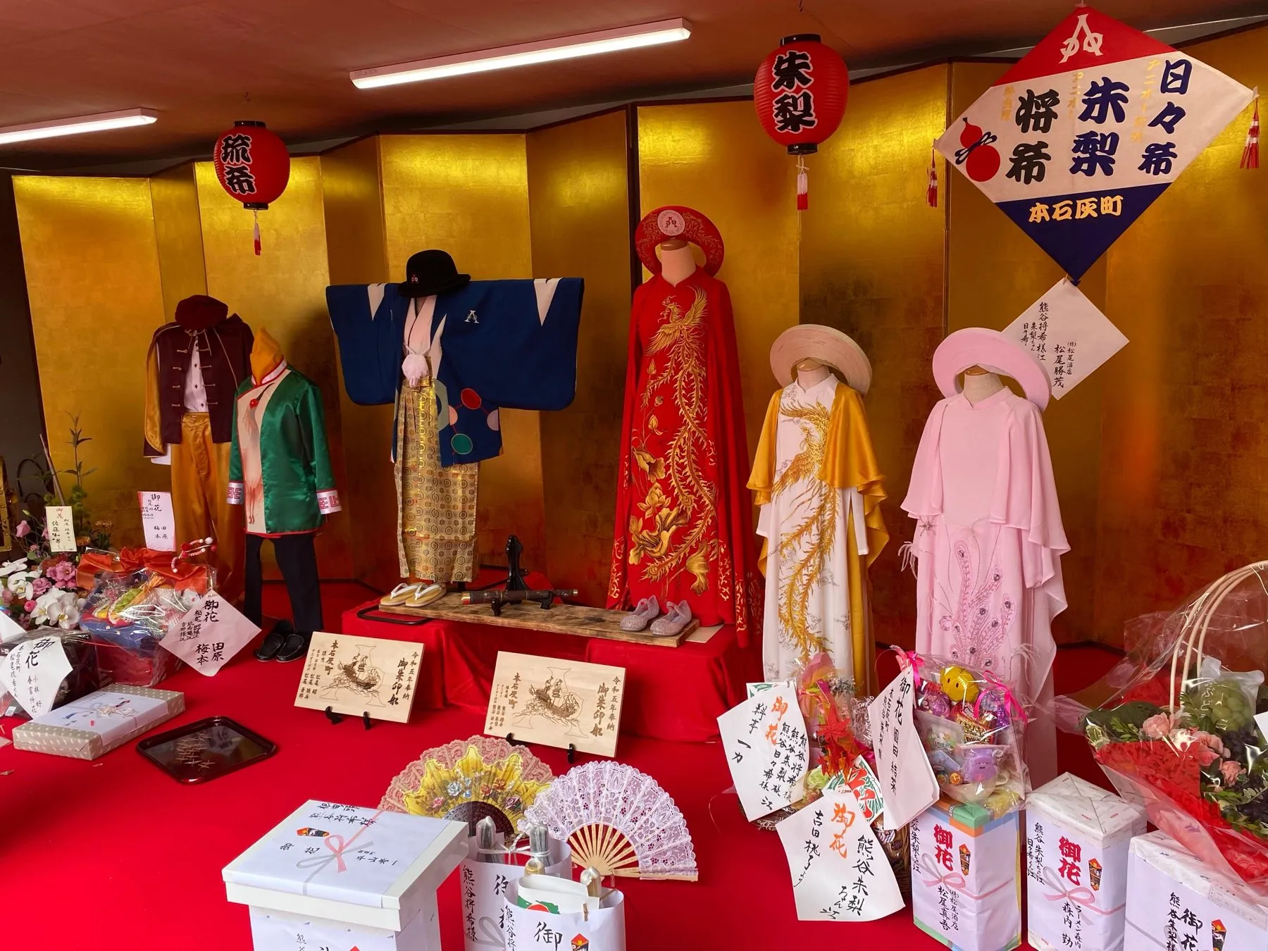 金屏風の前に並ぶ衣装と帽子