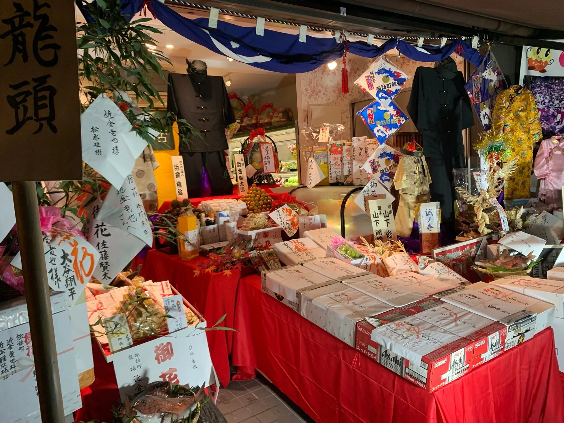 「龍頭」の札と、衣装や御花の並ぶ店先